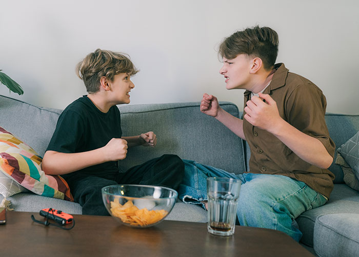 Two kids argue on a couch with snacks nearby, focusing on parenting dynamics. Two kids argue on a couch with snacks nearby, focusing on parenting dynamics.