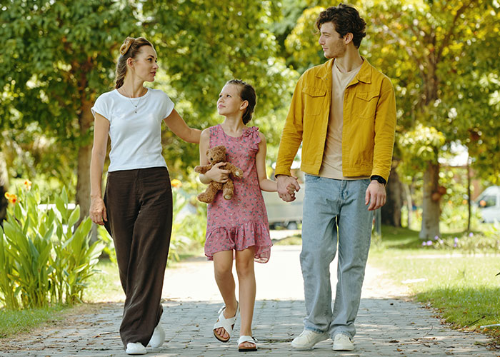 Couple walking with daughter in the park, capturing family time with kids at home, holding hands and carrying a teddy bear. Couple walking with daughter in the park, capturing family time with kids at home, holding hands and carrying a teddy bear.