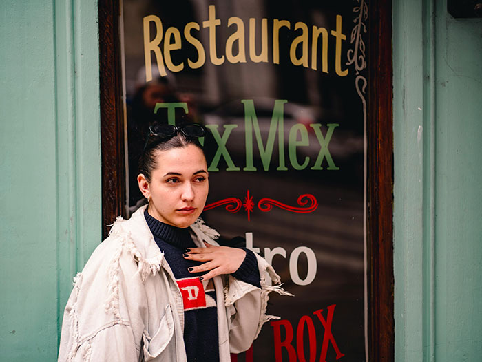 Woman in front of TexMex restaurant window, wearing a casual jacket, illustrating family food boundaries.