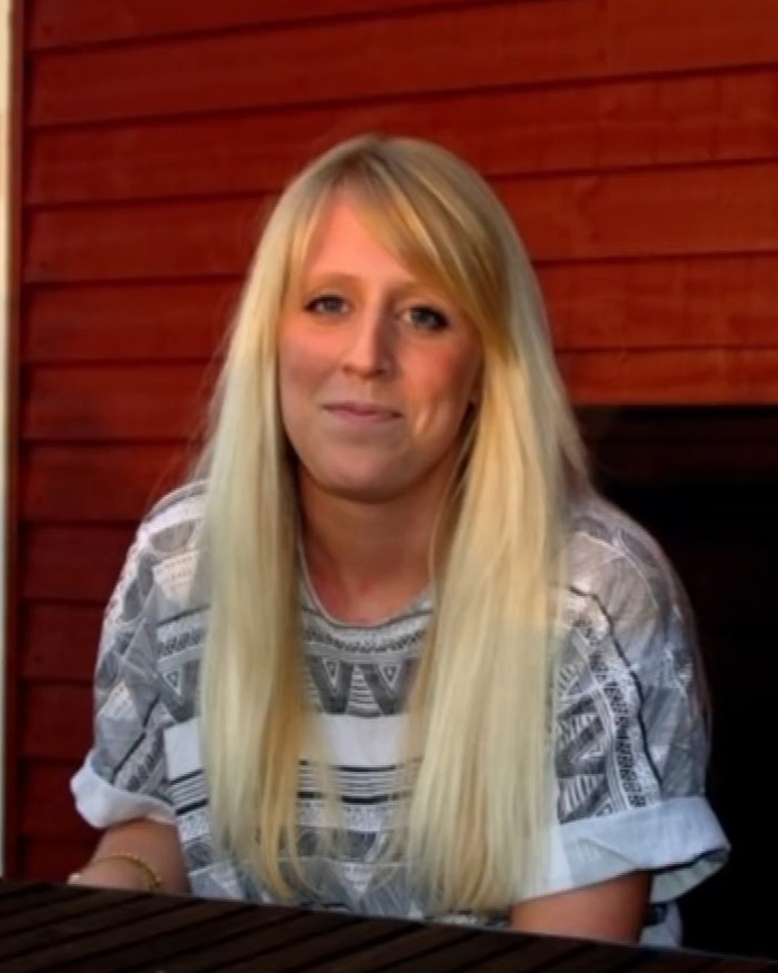 Woman with long blonde hair and patterned shirt, before transformation into Barbie look.