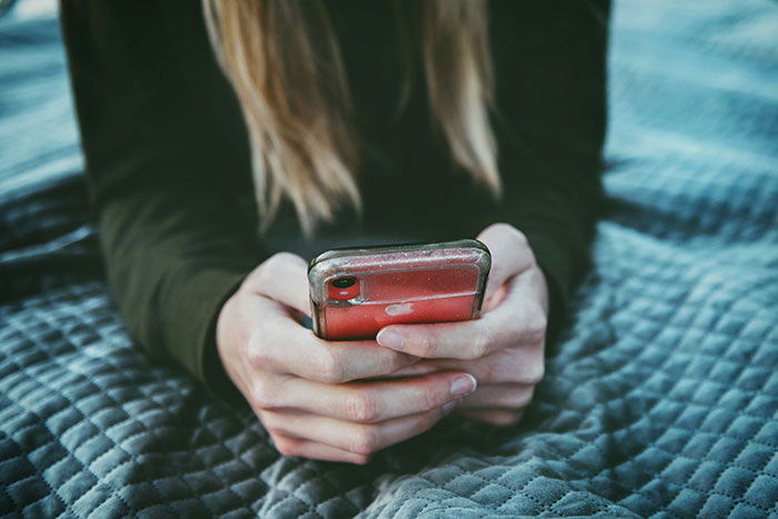 Woman holding a smartphone, indicating a conversation where she addresses oversharing.