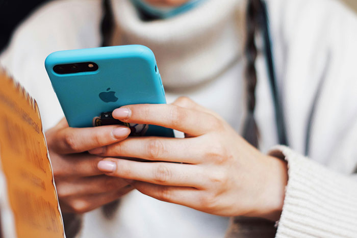 Person typing on a smartphone in a cozy setting, focusing on a personal celebration event.