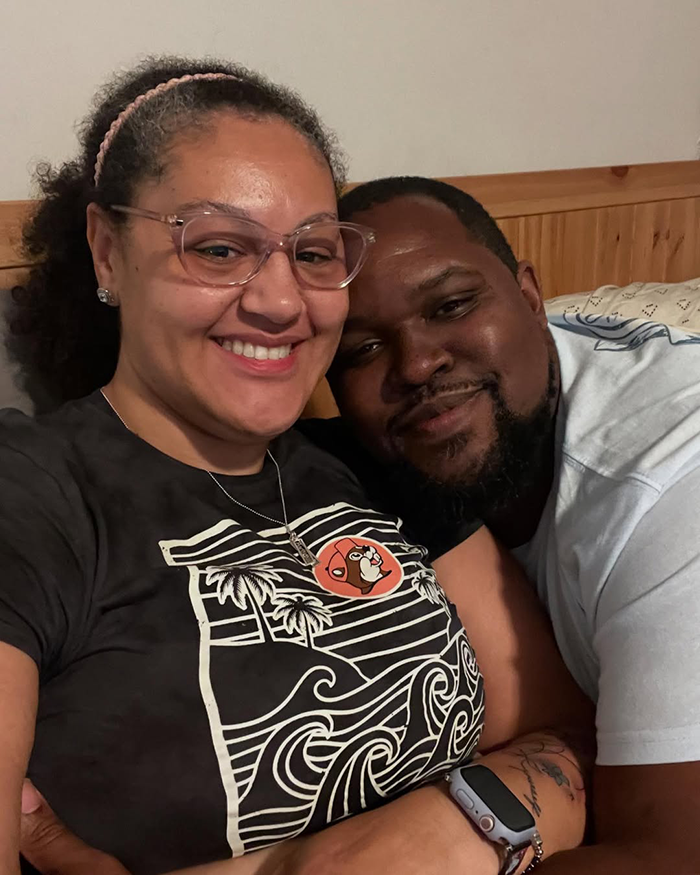 Smiling couple sitting close together indoors, illustrating a mass debate over inappropriate wedding dress choices.