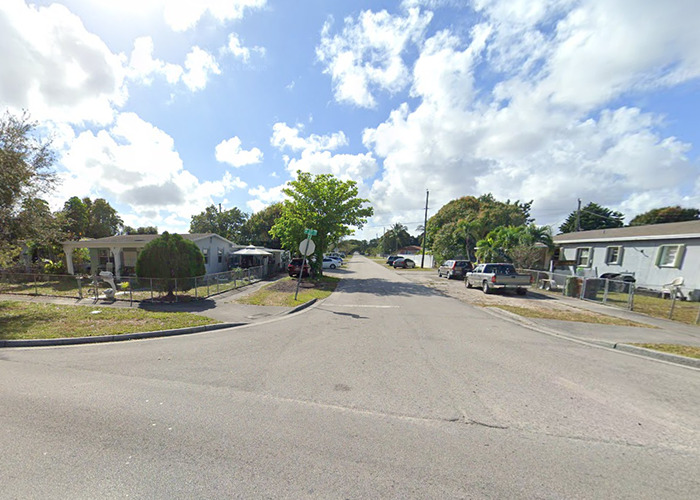 Residential street intersection on a sunny day, showcasing neighborhood houses and parked cars. Residential street intersection on a sunny day, showcasing neighborhood houses and parked cars.