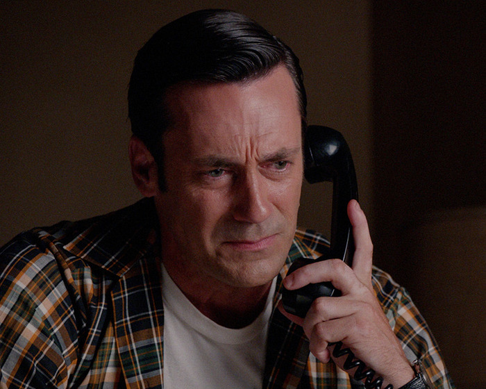 A man in a plaid shirt on a vintage phone, conveying concern, related to Jon Hamm university controversy.