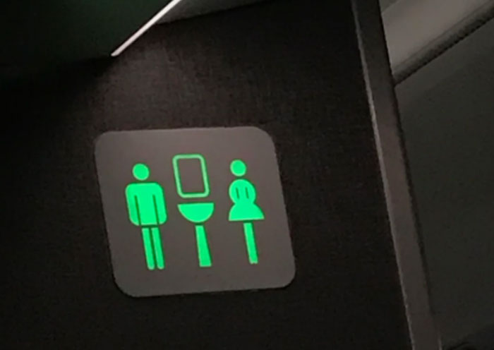 Airplane bathroom sign showing gender symbols, related to worst plane seatmates.