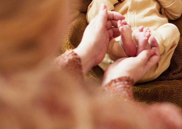 Person holding a baby’s feet, capturing a touching moment related to worst plane seatmates experience.