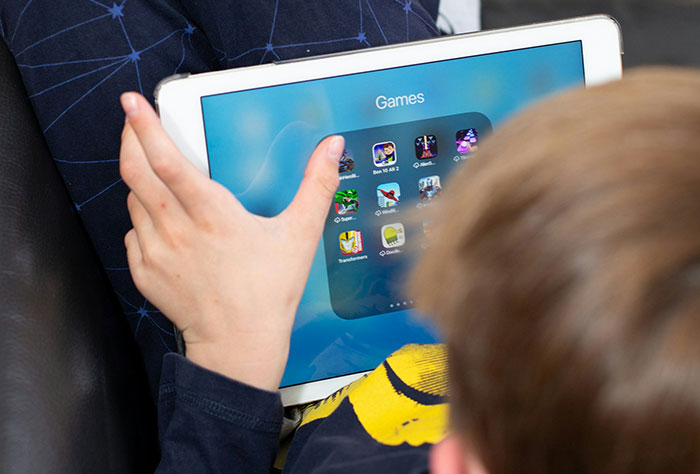 Child playing games on a tablet while sitting on a plane, illustrating worst plane seatmates.