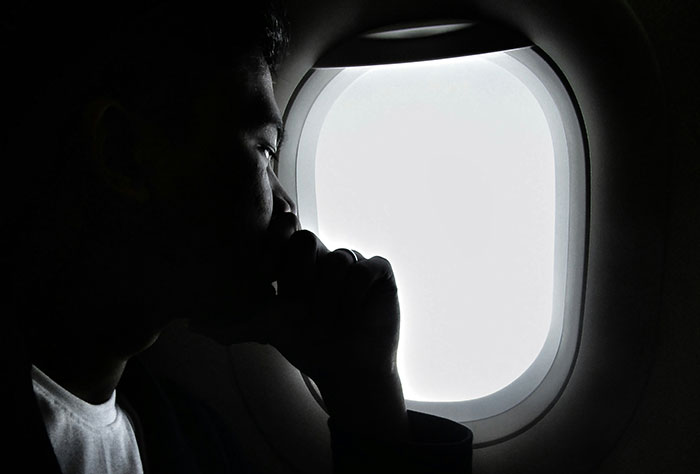 Passenger gazing out airplane window, contemplating the experience of having a difficult plane seatmate.