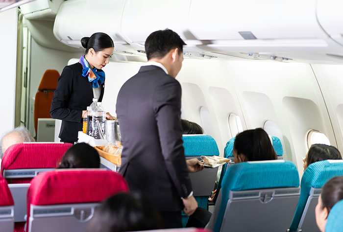 Flight attendants serving snacks to passengers on a plane.