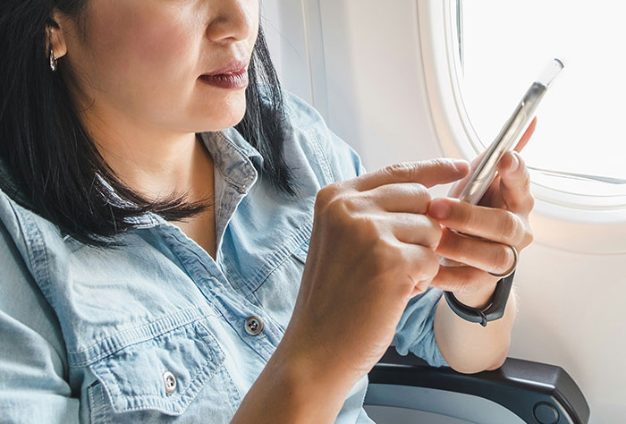 Person using a smartphone on a plane, illustrating typical plane seatmate behavior.