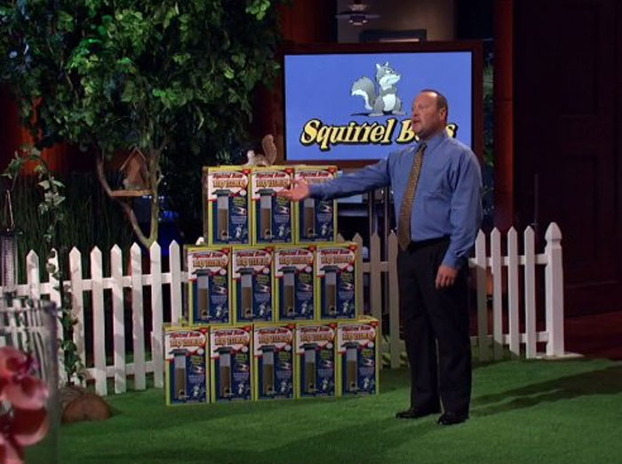Presenter showcasing boxes of a failed product on Shark Tank, highlighting notable Shark Tank products that completely flopped.