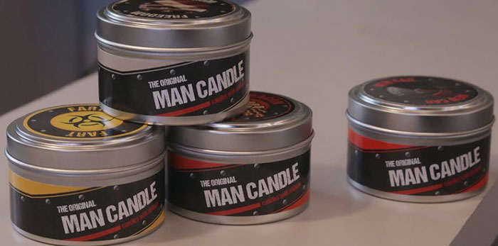 Stack of man candle tins, a notable Shark Tank product that completely flopped, displayed on a white surface.