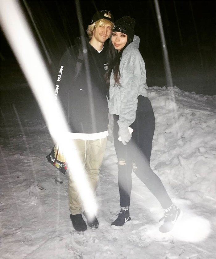 Two people including streamer xQc standing in the snow, wearing winter clothes at night, related to xQc net worth discussions.