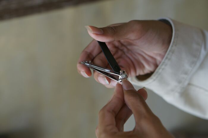 Hands using nail clippers for hygiene, ensuring fresh and clean appearance.