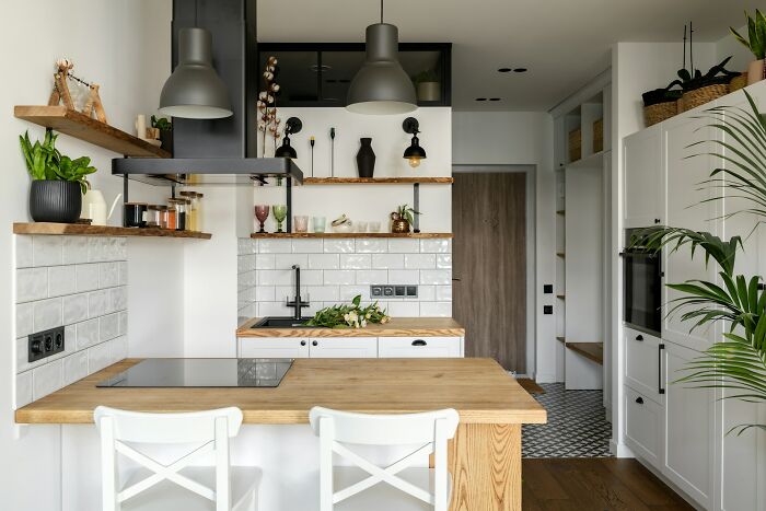 Modern kitchen with minimalistic decor and vessel sink, featuring wooden accents and hanging lights.
