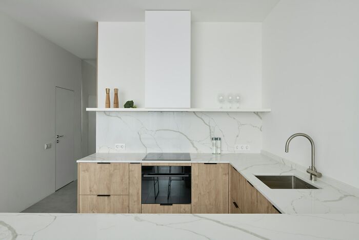 Modern kitchen with a sleek sink, wooden cabinets, and marble countertops, showcasing contemporary home design trends.