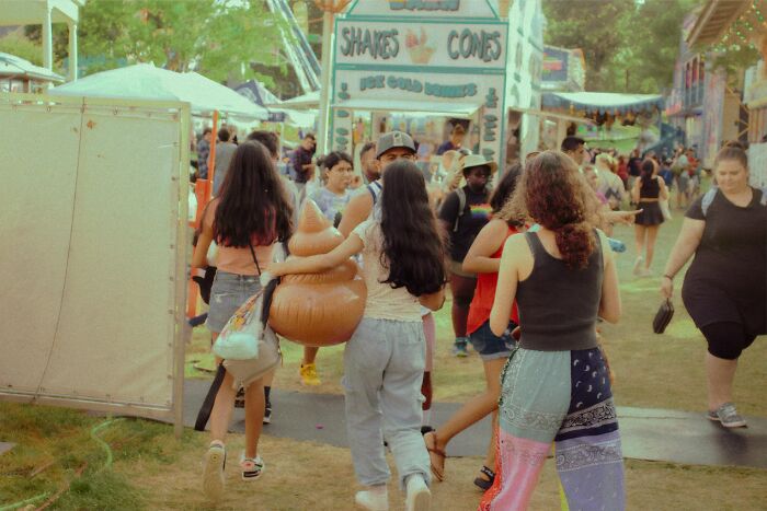 People at a fair, with one carrying a large brown inflatable toy.