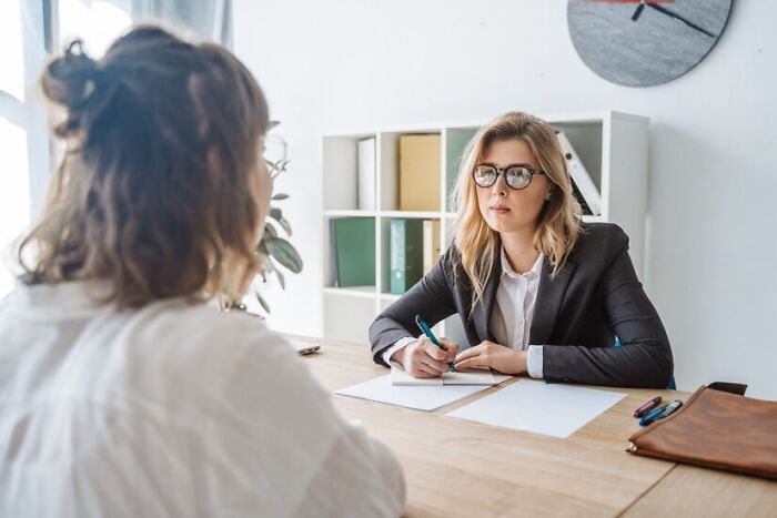 Two women at a desk during a job interview, highlighting red flags in conversation.