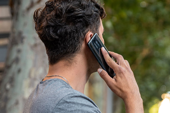 Man outside talking on a smartphone, wearing a grey shirt; symbolic of a reality check conversation. Man outside talking on a smartphone, wearing a grey shirt; symbolic of a reality check conversation.