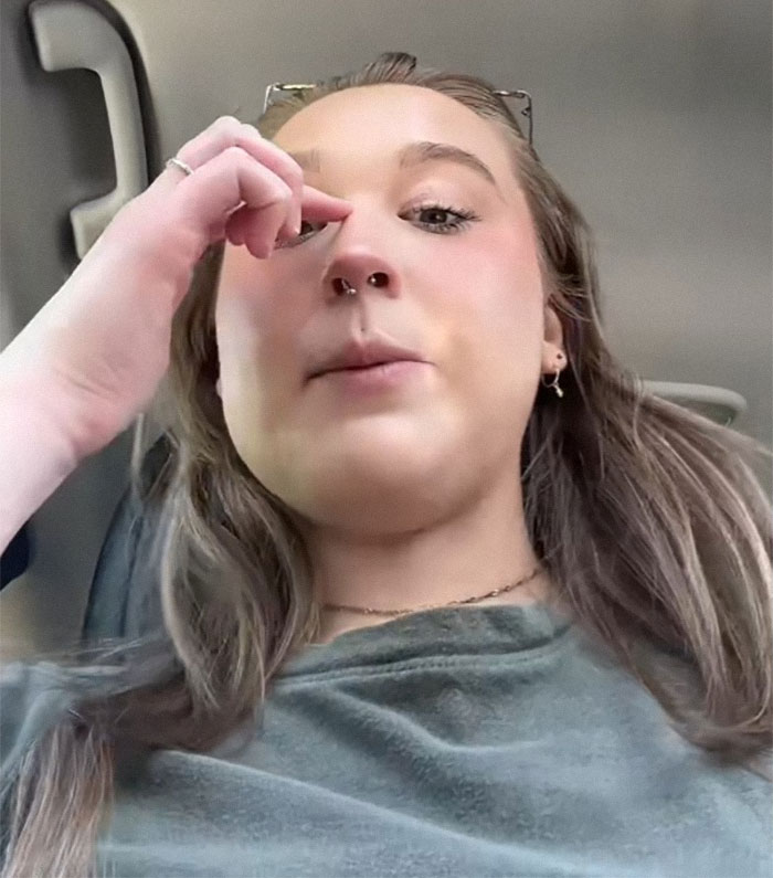 Young woman with POTS in a car, appearing frustrated while addressing harassment about her disability status.