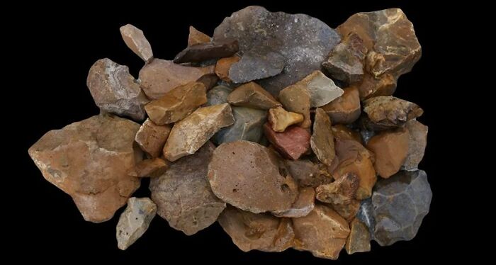 Collection of ancient archeological discoveries including various stone tools and artifacts on a black background.