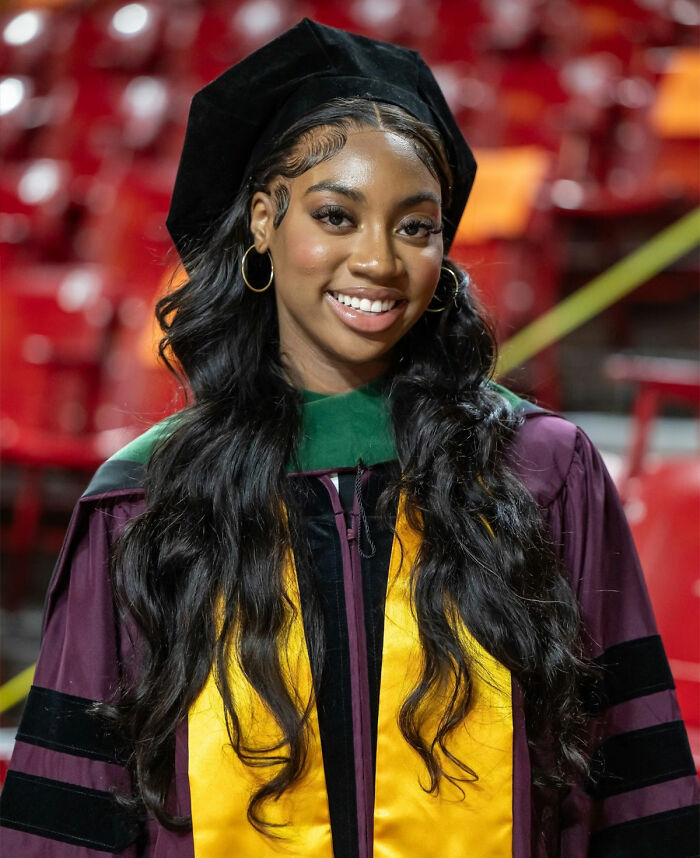 Young woman in graduation gown and cap smiling, representing unusual wonderful events and interesting facts.