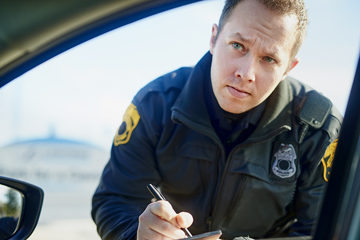 Police officer writing a speeding ticket for a driver, representing a cop wrongfully tickets driver for speeding story. Police officer writing a speeding ticket for a driver, representing a cop wrongfully tickets driver for speeding story.