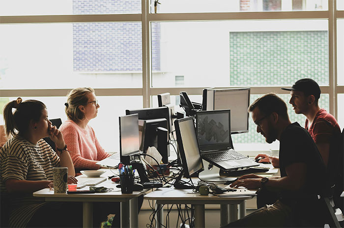 Office workers focused on computer screens in a modern workspace illustrating attention seeking in a professional setting.