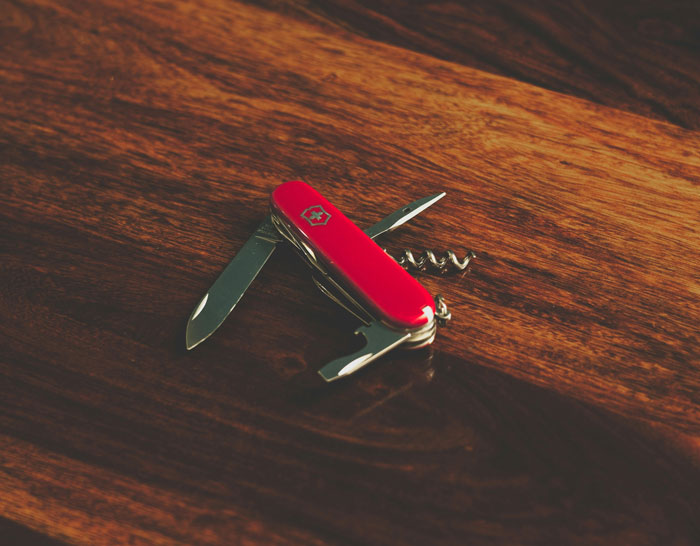 Red Swiss Army knife with multiple tools extended, symbolizing self-defense in unsuccessful mugging attempts.