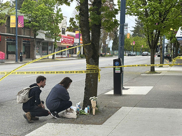 Two people crouch beside a memorial at a Vancouver street scene after heartbreaking attack involving Hallmark actor.