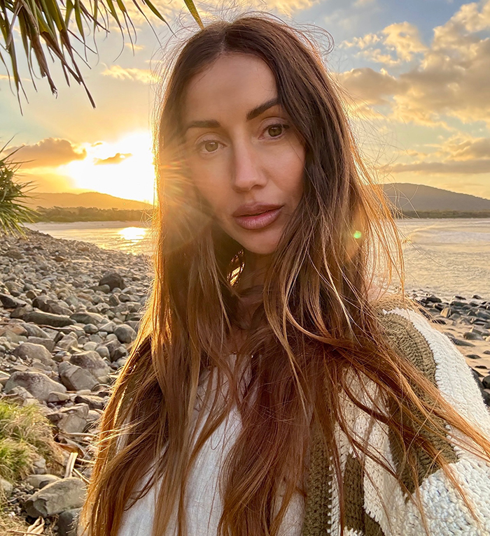 Big Brother star shows stunning body transformation after ditching veganism for meat, posing at sunset by rocky beach.