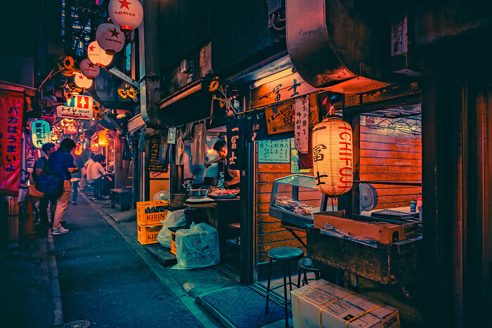 Narrow urban street scene at night with warm lantern light, showcasing vibrant street photography moments by talented photographers.