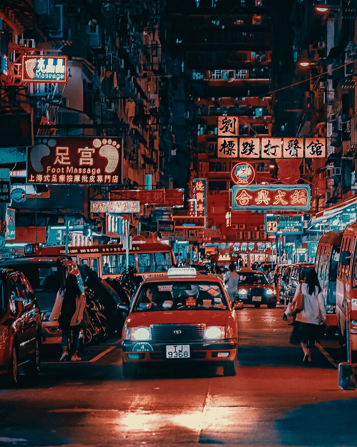 Nighttime street photography moment showcasing busy city traffic and illuminated neon signs in an urban setting by talented photographers.
