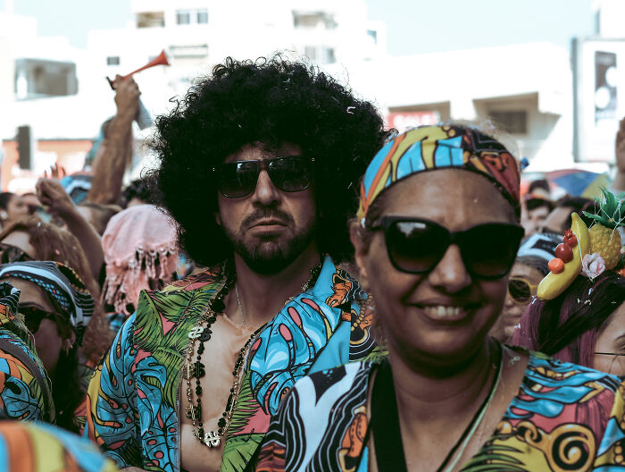 Crowd wearing colorful outfits and sunglasses, capturing vibrant street photography moments at a lively outdoor event.