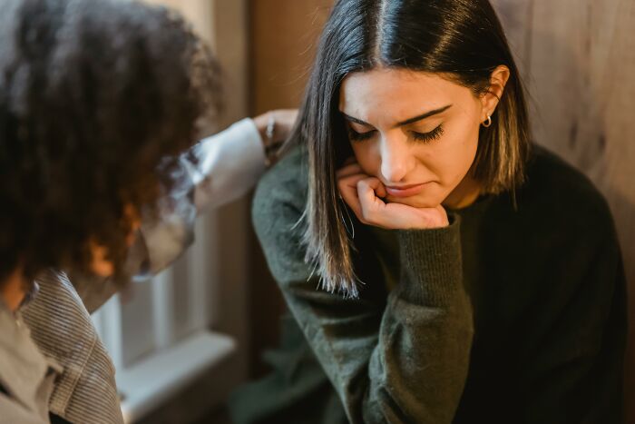 Woman looking down with concern while another person offers comfort in a casual setting, related to Red Flag Poll.