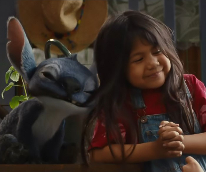 Young girl smiling next to a redesigned Stitch character in Lilo & Stitch's live-action, sparking Disney fans outrage.