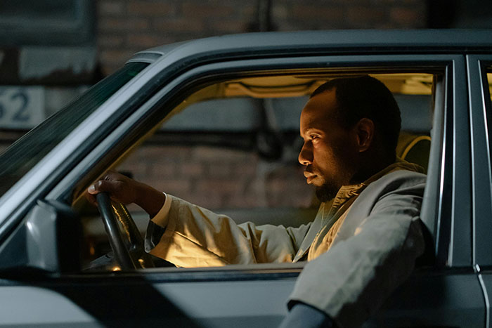 Man with a scared gut feeling driving a car at night, appearing tense and focused on the road ahead.