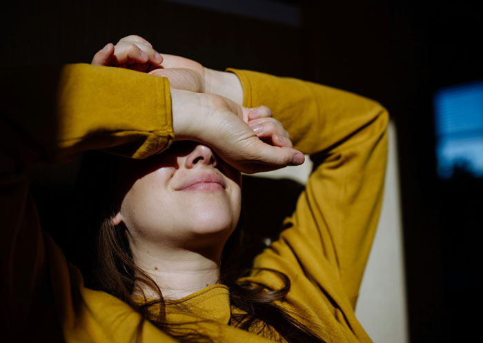 Woman in a yellow shirt covering her eyes, reflecting on the reason she lost a good friend after years of friendship.