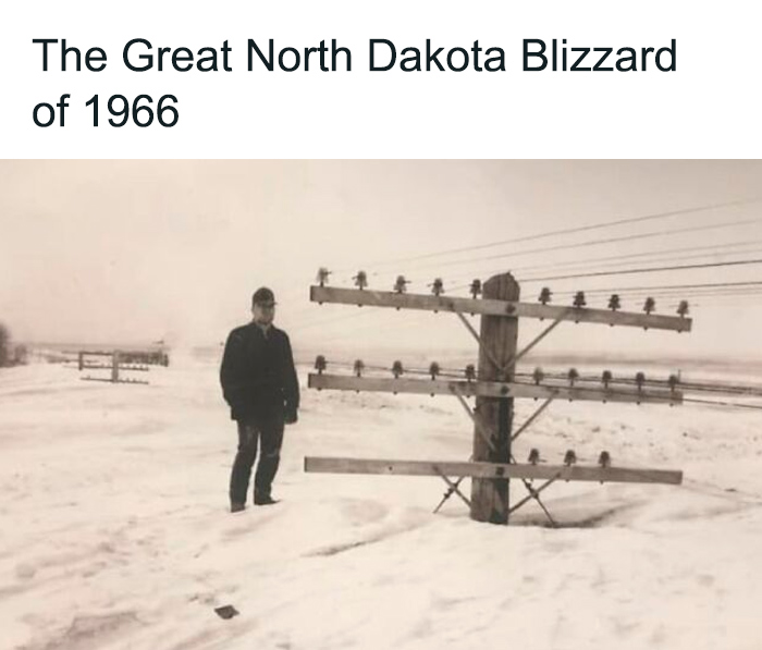 Man standing in deep snow next to telephone poles during the Great North Dakota blizzard, a monumental life moment frozen in time.