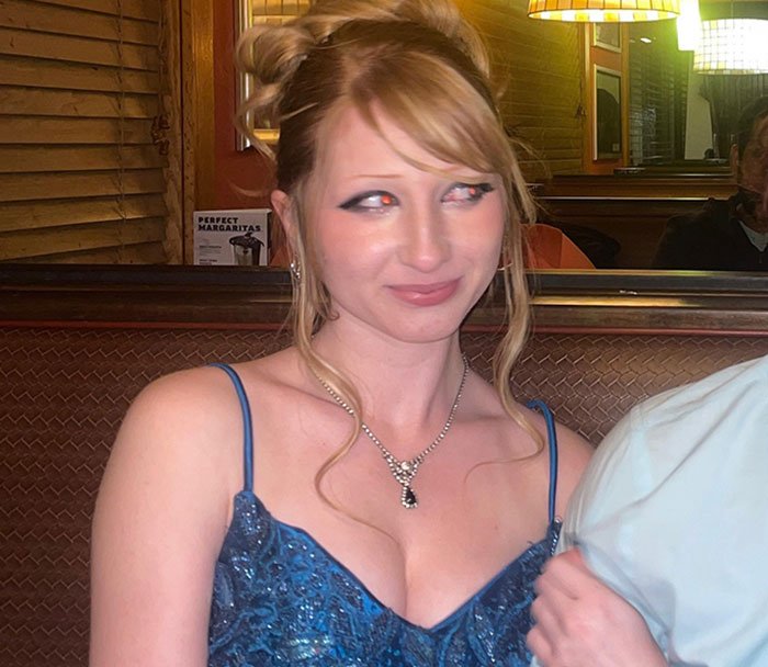 Teen girl in a blue dress and necklace at a restaurant, related to expulsion from Christian school over trans prom date debate.