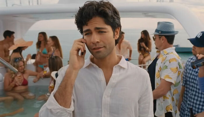 Man in white shirt talking on phone at a lively party scene, illustrating miscast actors in popular movies.