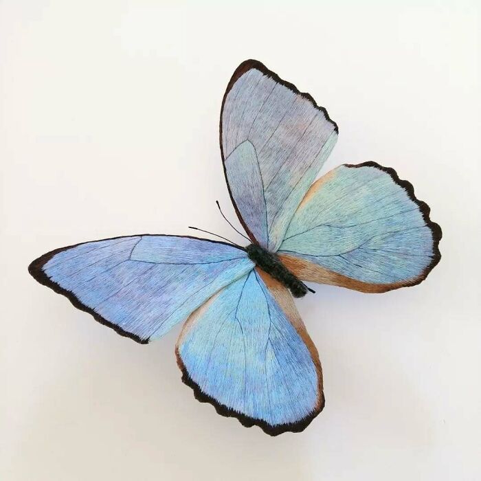 Blue embroidered fiber butterfly with delicate stitching and black-edged wings crafted by Yumi Okita.