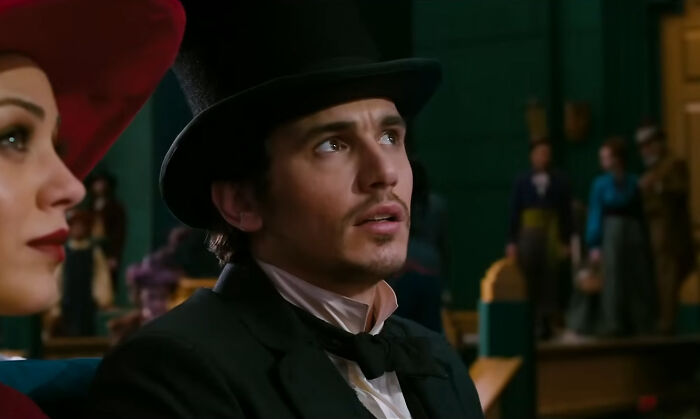 Man in a top hat and black suit with a woman in a red hat, representing miscast actors in famous movies.