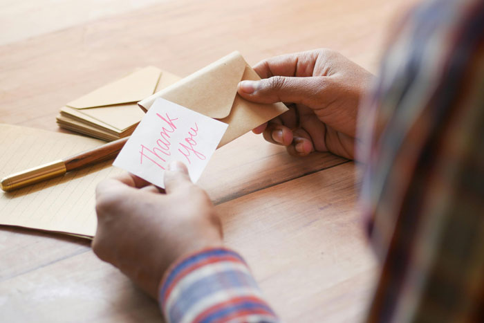 Person holding an envelope with a thank you note, illustrating a weird habit linked to being raised poor.