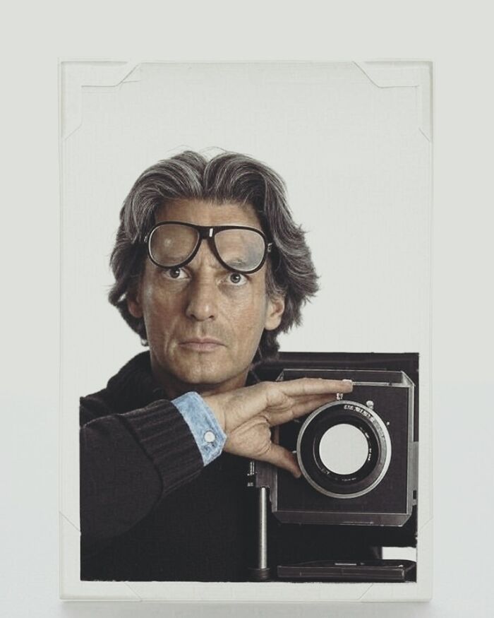 Man with vintage camera and large glasses resting on forehead, capturing a unique side of history not found in textbooks.