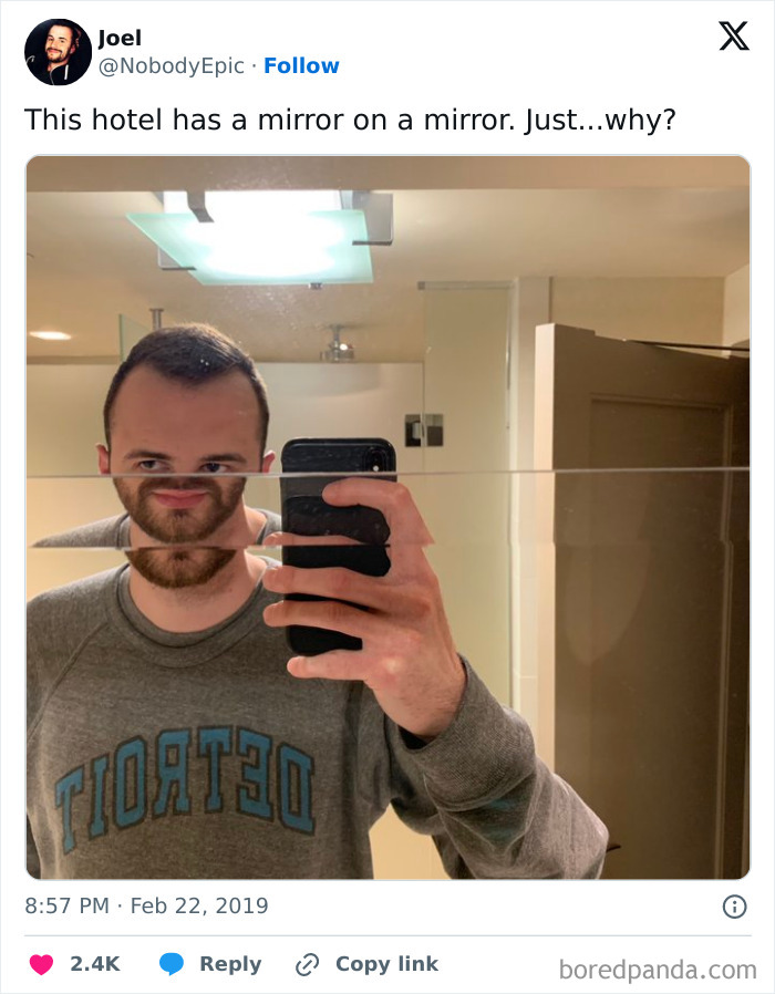Man taking selfie in bathroom with two mirrors creating distorted face, illustrating dumb interior design decisions and lack of common sense.