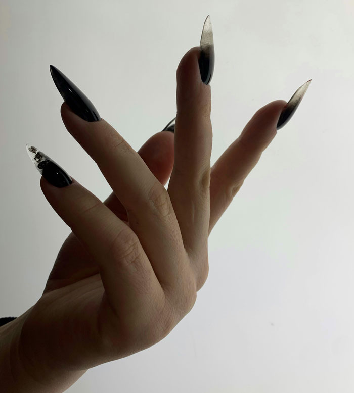 Hand with long black and clear nails, illustrating problematic behaviors women get a pass for according to men.