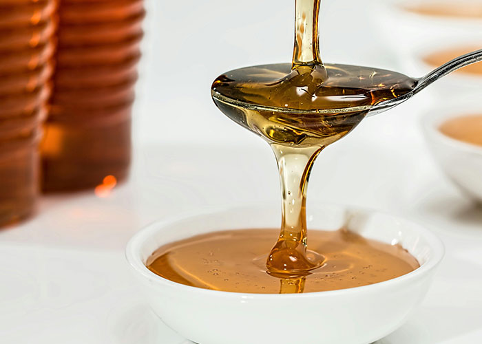Honey pouring from a spoon into a white bowl, illustrating one of the surprisingly entertaining facts shared in this thread.