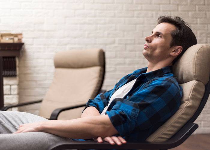 Young man sitting in a chair looking thoughtful indoors, reflecting on things everyone does but doesn’t talk about.